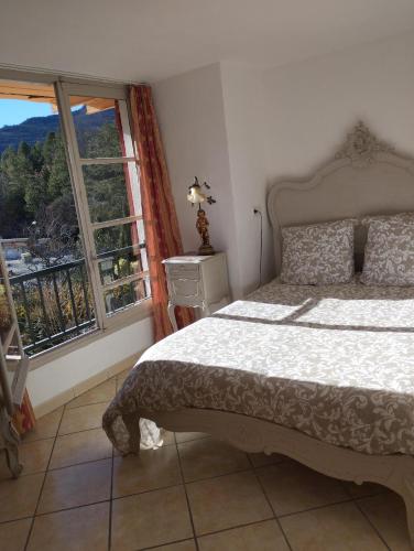 une chambre avec un lit et une grande fenêtre dans l'établissement Aux logis du Lac de Castillon, à Saint-Julien-du-Verdon