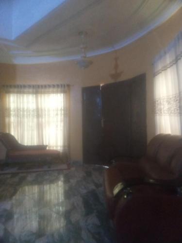 uma sala de estar com um sofá e duas janelas em Residence Ola em Porto Novo