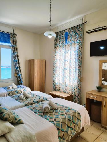 a hotel room with two beds and a window at Pelineon Rooms in Chios