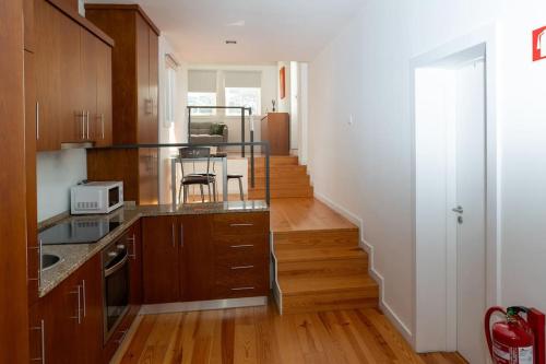 eine Küche mit Holzschränken und einer Treppe in der Unterkunft Moniz Terrace in Guimarães