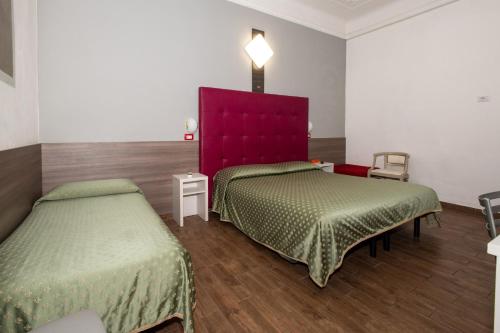 a bedroom with two beds and a red headboard at Hotel Piola in Milan