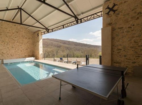 une piscine intérieure avec une table de ping-pong dans un bâtiment dans l'établissement Domaine de Balesta, à Roquefort-sur-Garonne