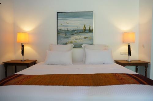 a bedroom with a white bed with two lamps at Villa Blue Lotus Katunayake in Katunayake