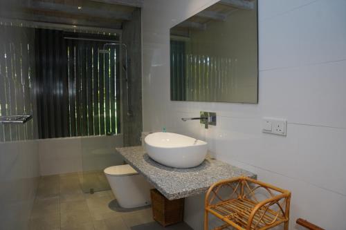 W łazience znajduje się umywalka, toaleta i lustro. w obiekcie Villa Blue Lotus Katunayake w mieście Katunayake
