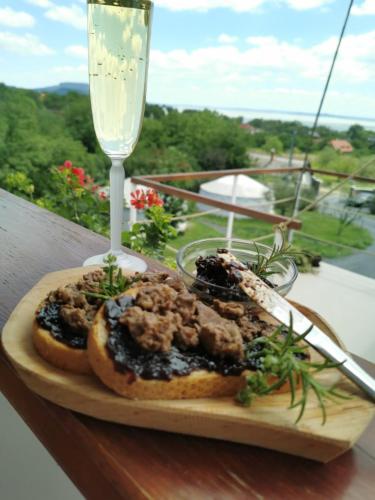a sandwich on a cutting board next to a wine glass at Jurta Hotel Balatongyörök in Balatongyörök