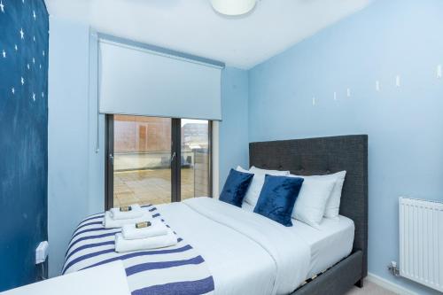 a bedroom with a large bed with blue walls at Modern 2BR wPatio & free parking, Canning Town in London