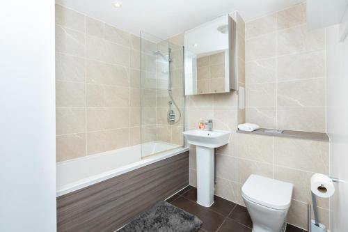 a bathroom with a toilet and a sink and a shower at Modern 2BR wPatio & free parking, Canning Town in London