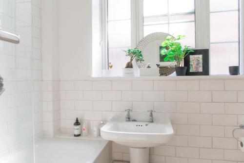 a white bathroom with a sink and a bath tub at Bright wood-floor apartment near Parliament in London