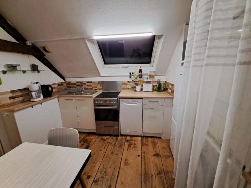uma pequena cozinha com armários brancos e uma janela em Atypique et douillet nid em Vougeot