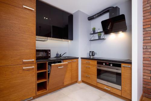 cocina con armarios de madera y microondas en Industrial Apartment Fredry with Parking by Renters, en Cracovia