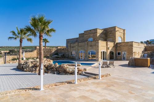 a building with a swimming pool and palm trees at L-Eremita Boutique Hotel in Qala