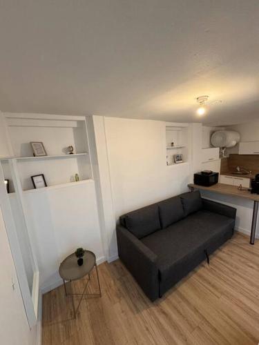 un salon avec un canapé noir et une table dans l'établissement Saint Marc - studio 1er Etage Cours, à Rouen