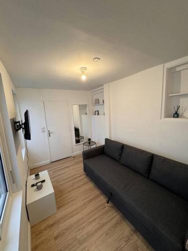 un salon avec un canapé noir et une table dans l'établissement Saint Marc - studio 1er Etage Cours, à Rouen