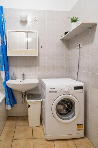 a bathroom with a washing machine and a sink at Tomka Apartman in Szeged