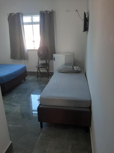 - une chambre avec 2 lits et une fenêtre dans l'établissement Pousada Belaisa, à Matinhos