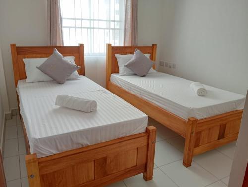 2 Einzelbetten in einem Zimmer mit Fenster in der Unterkunft UNIPLEX HOMES in Mombasa