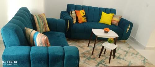 eine blaue Couch mit bunten Kissen und einem Tisch in der Unterkunft UNIPLEX HOMES in Mombasa