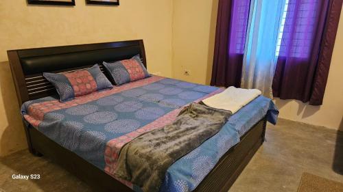 a bed in a bedroom with purple curtains at LDS Homestay in Rāmnagar