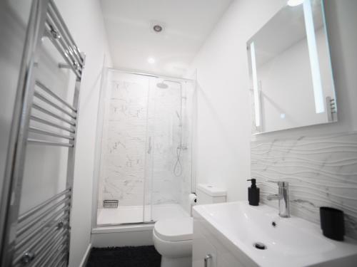 a white bathroom with a shower and a toilet at Stunning City Apartment - Parking 