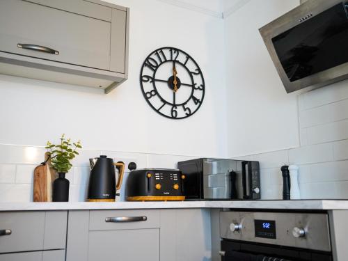 a clock on the wall above a kitchen counter at Boutique Docks Apartment - Parking in Gloucestershire