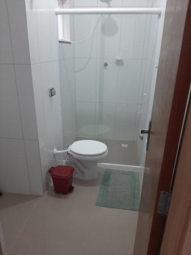 La salle de bains blanche est pourvue d'une douche et de toilettes. dans l'établissement Pousada Belaisa, à Matinhos