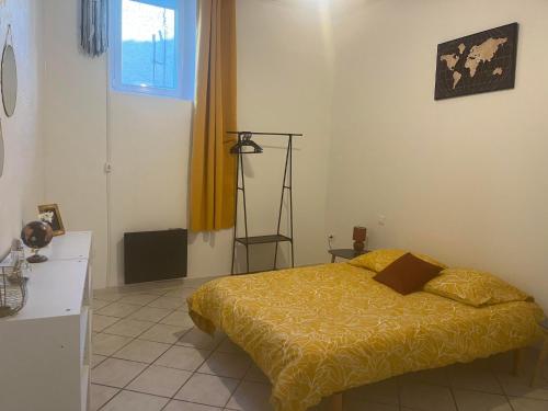 une chambre avec un lit avec une couverture jaune dans l'établissement Chez Pat, Appartement centre ville de Vias(34), mer à 2,5km, à Vias