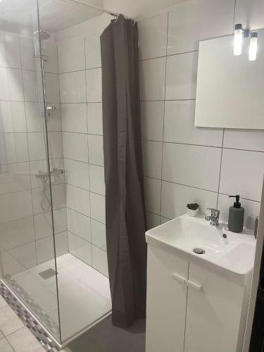 une salle de bain blanche avec une douche et un lavabo dans l'établissement Chez Pat, Appartement centre ville de Vias(34), mer à 2,5km, à Vias
