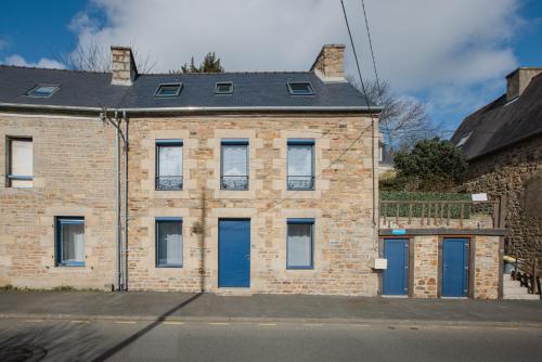 a brick building with blue doors on a street at Gîte Estuaire du Trieux in Lézardrieux