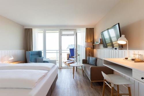 a hotel room with a bed and a living room at Wyn. Strandhotel Sylt in Westerland (Sylt)