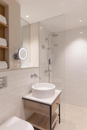 a white bathroom with a sink and a shower at Wyn. Strandhotel Sylt in Westerland (Sylt)