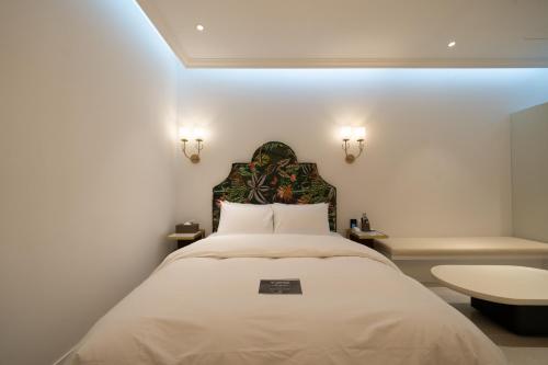 Schlafzimmer mit einem großen weißen Bett mit Kopfteil in der Unterkunft Lua Premium Drive-In Hotel in Pocheon-si