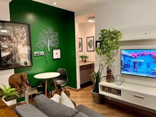 a living room with a green wall and a tv at Linda vista perto da Paulista com piscina/garagem in Sao Paulo