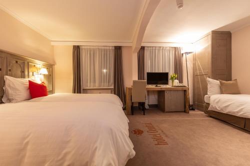 クランにあるHotel Central, Spa & lounge barのベッド2台とデスクが備わるホテルルームです。