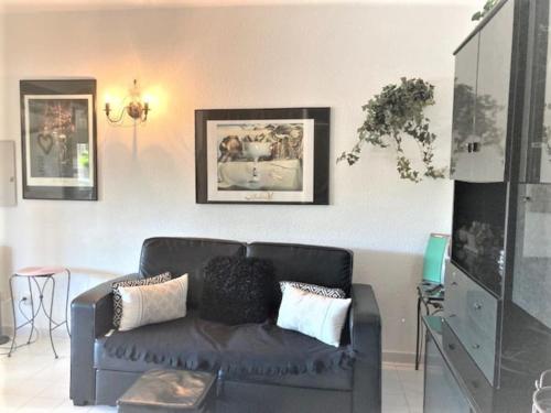 un salon avec un canapé en cuir noir dans l'établissement Villa 53, Port Vénus au village naturiste, au Cap d'Agde