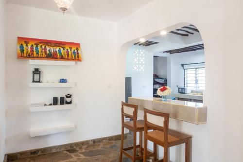 a kitchen with a bar with chairs and a sink at Villa Black Pearl - new private Villa in Diani Beach