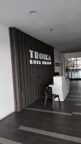 a lobby with a chair and a wall with a sign at The Penthouse TROIKA KOTA BHARU in Kota Bharu