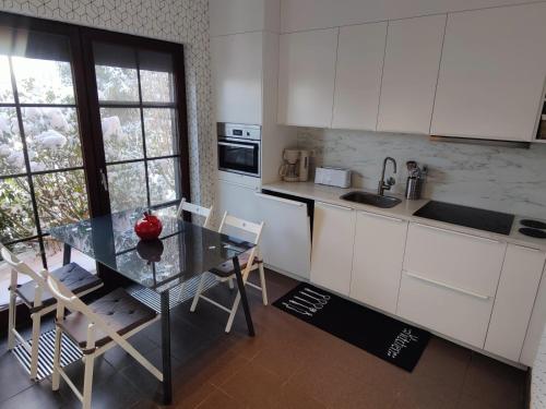 a kitchen with a glass table and white cabinets at Sluizen aan de Jeker in Tongeren