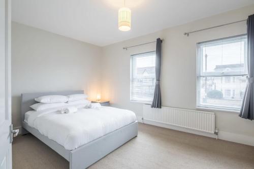 a white bedroom with a bed and two windows at Superb Central 2 Bed Home in Cherry Hinton