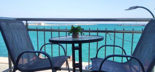 einen Tisch und Stühle auf einem Balkon mit Blick auf das Wasser in der Unterkunft Pelineon Rooms in Chios