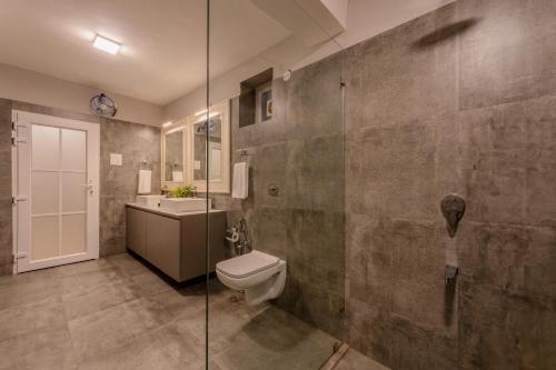 a bathroom with a toilet and a glass shower at Phoenix by Hireavilla 5BR Villa with Pool in Colvale in Colovale