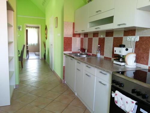 巴拉頓萊萊的住宿－Ferenc Vendégháza，厨房配有白色橱柜和绿色墙壁