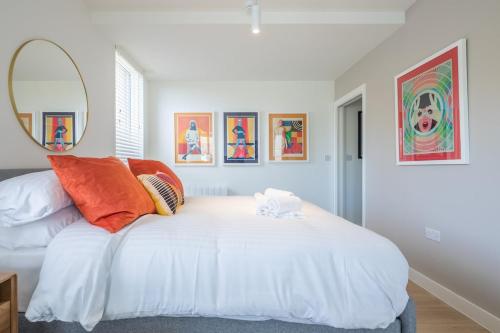 a bedroom with a large white bed with orange pillows at Luxury City Centre Apartment - Stunning Water View in Cambridge