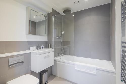 La salle de bains blanche est pourvue d'une baignoire, de toilettes et d'un lavabo. dans l'établissement Luxury City Centre Apartment - Stunning Water View, à Cambridge