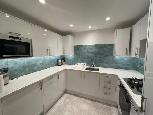 una cocina con armarios blancos y fregadero en Large Luxurious CENTRAL Private Terrace - For 6, en Londres