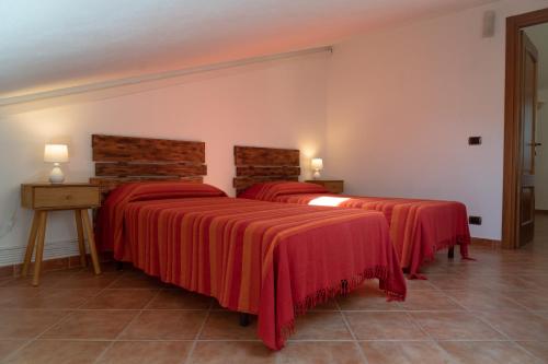 2 camas en una habitación con mantas rojas en Casa Madì, en Porto Torres