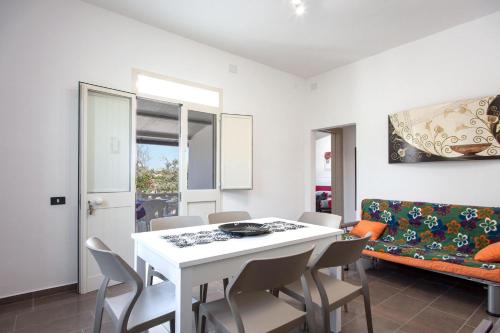 a dining room with a table and chairs and a couch at Villa Sabbia Magica 100 meters from sea - Happy Rentals in Porto Cesareo