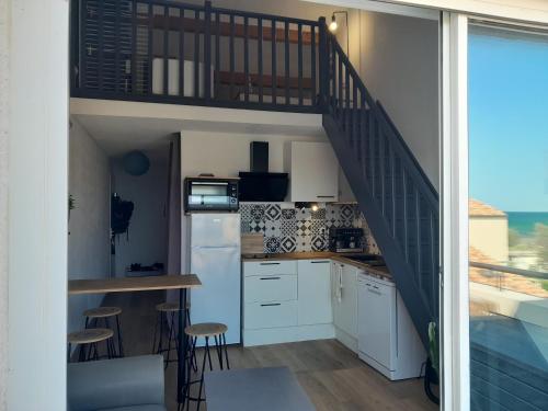 une cuisine avec des placards blancs et un escalier dans l'établissement Le Sablé, à Frontignan