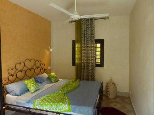 a bedroom with a bed and a ceiling fan at O Cupidon Doré in Sali Nianiaral