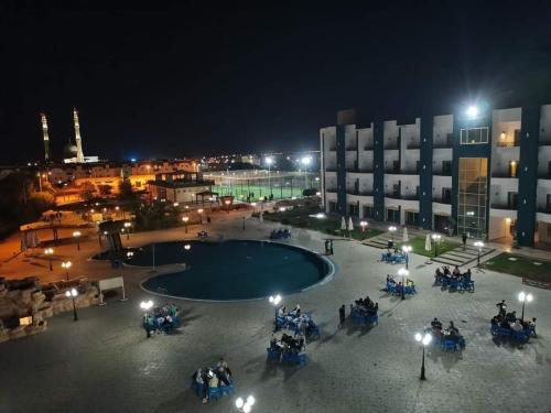 un grupo de personas sentadas alrededor de una piscina por la noche en Sharm el shiekh sports city en Sharm El Sheikh