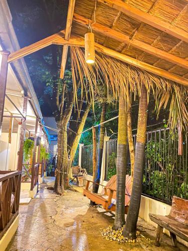 a patio with a bunch of palm trees and a bench at Aquaholik Traveler's Lodge in El Nido